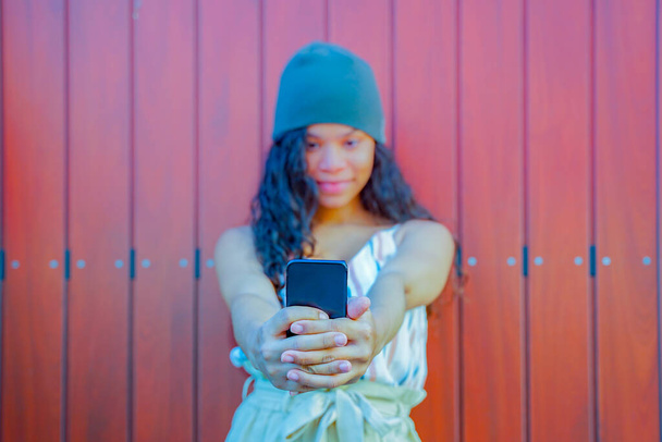 Melko nuori onnellinen nainen tekee selfie älypuhelimella. Iloisen naisen muotokuva, joka tekee selfietä. Kuva ruskean puutaustan päällä - Keskity sormikäsiin. Kuva
 - Valokuva, kuva