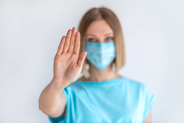 Приваблива жіноча медсестра, яка показує знак стоп з жестом рук ізольована на білому тлі. Медична концепція інфекції
 - Фото, зображення