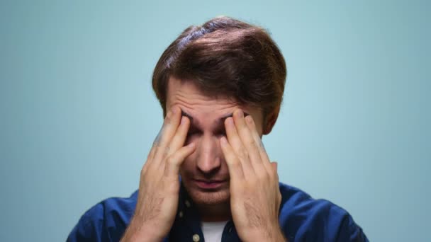 頭痛のある疲れた男の肖像画。ストレス男顔上の青の背景 - 映像、動画