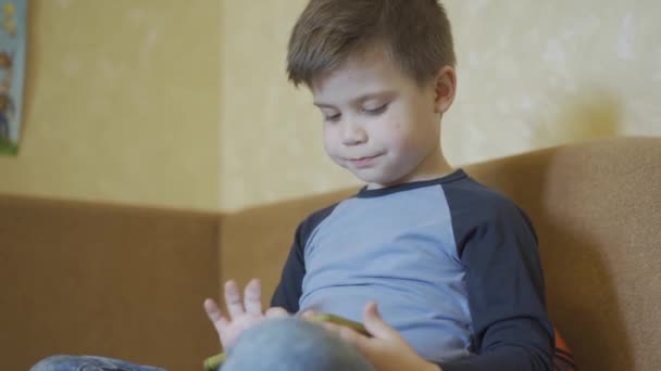 Boy fixes his hair while playing games on smartphone. - Imágenes, Vídeo