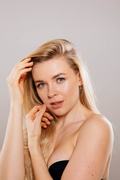 close up portrait of beautiful blonde woman posing in studio against nude background - Photo, Image