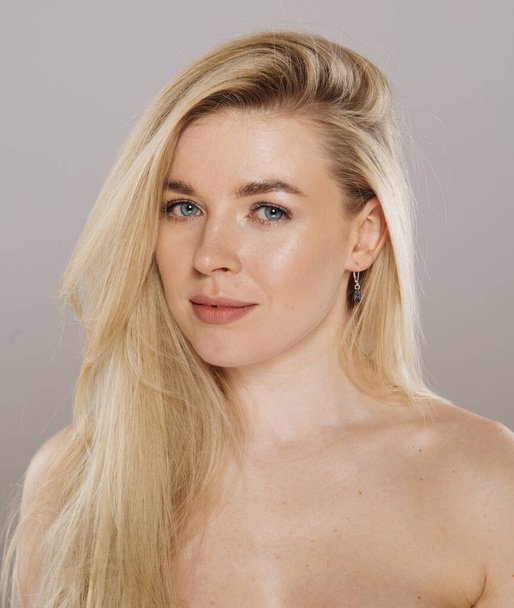 close up portrait of beautiful blonde woman posing in studio against nude background - Photo, Image
