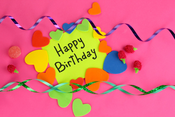 Card "Happy Birthday" surrounded by festive elements on pink background - Фото, изображение
