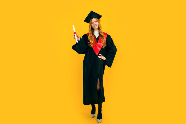 Plná délka, šťastná krásná dívka absolvent šťastný a bavte se s diplomem na žlutém pozadí. Koncept slavnostní prezentace diplomů - Fotografie, Obrázek
