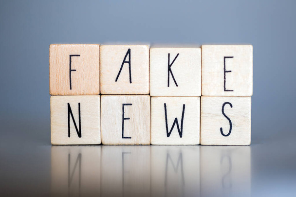 Cupola di legno con le parole fake news su sfondo grigio, concetto di fake news social media close-up
 - Foto, immagini