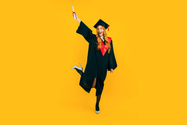 Full length, happy beautiful girl graduate happy and have fun with diploma on yellow background. The concept of the ceremonial presentation of diplomas - Fotografie, Obrázek