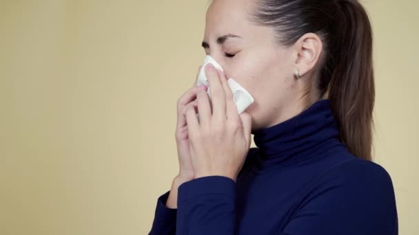 Portrait of young woman blows her nose into napkin, sneezes and coughs, isolated - Filmmaterial, Video