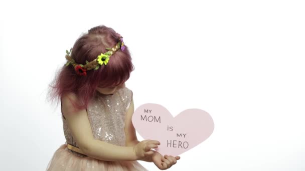 Child girl princess holds pink paper heart with text about mother. Mothers day - Footage, Video