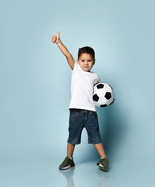 Cute boy playing football, happy child, young male teen goalkeeper enjoying sport game, holding ball, isolated portrait of a preteen smiling and having fun - Φωτογραφία, εικόνα