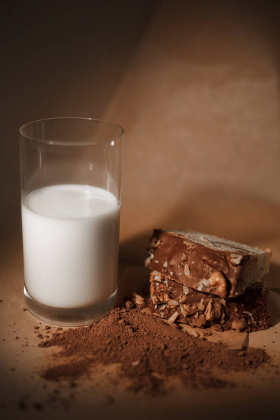 Čokoládové muffiny s mlékem na tmavém pozadí. Kakaový prášek, čokoládový muffin a sklenici mléka - Fotografie, Obrázek