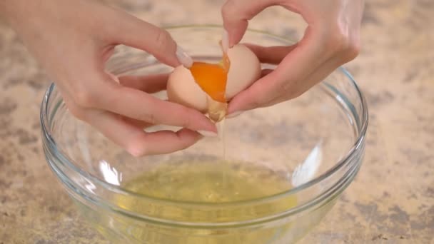 Női kéz eltöri a tojást, és elválasztja a sárgáját a fehértől.. - Felvétel, videó
