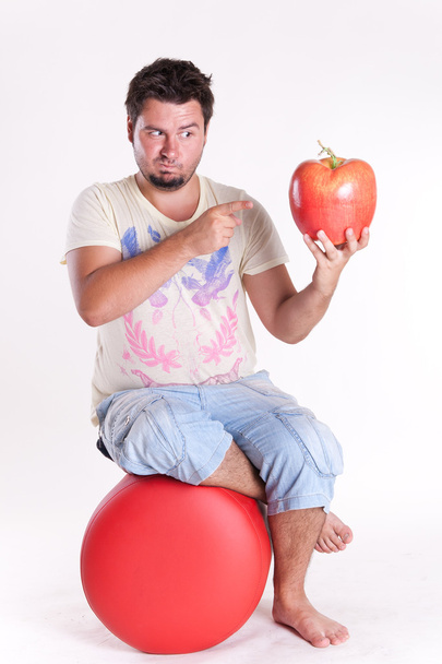 νεαρός άνδρας δαγκώνει ένα τεράστιο νόστιμο μήλο, σε λευκό - Φωτογραφία, εικόνα