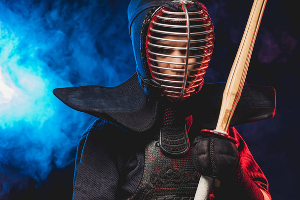 confident kendo fighter in armor practicing with bamboo sword - Fotó, kép