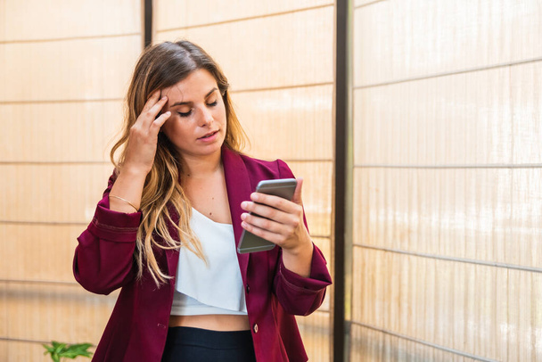 молодая деловая женщина видеозвонок по мобильному телефону, в офисе с закрытыми глазами
. - Фото, изображение
