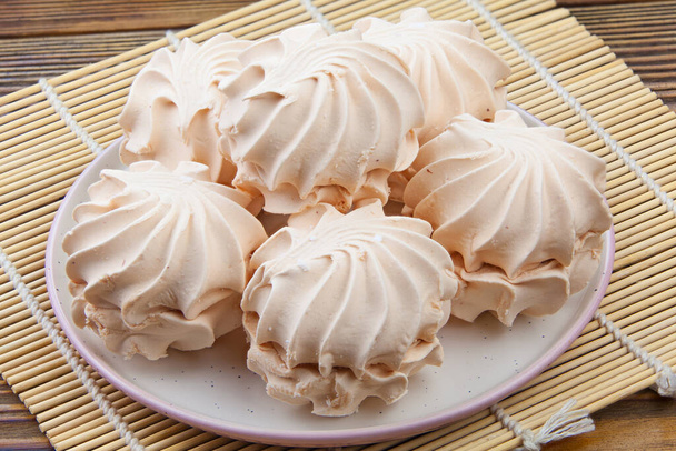 Herkullinen valkoinen vaniljavaahtokarkki lautasella puupohjalla
 - Valokuva, kuva