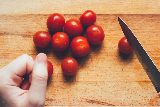 kotitekoinen pizza askel askeleelta ohje.DIY pizza askel 5.varovasti pilko tomaatit. Naisen kädet leikkaamalla tomaatti
 - Valokuva, kuva