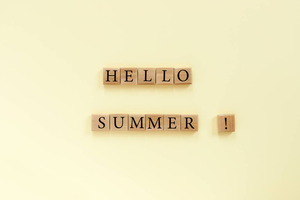 Wooden cubes with text "Hello summer" on yellow paper background - Foto, Imagen