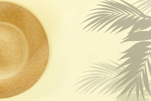 Chapeau de paille à la mode avec des feuilles de palmier sur fond de papier jaune - Photo, image