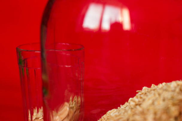 fotó piros háttér zab groats egy pohár és egy bank vízszintesen közel - Fotó, kép