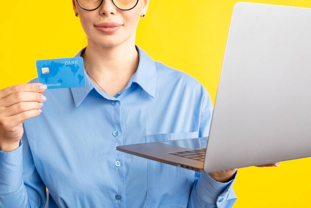Vista de cerca de la mujer en el shurt azul que sostiene el ordenador portátil y la tarjeta de crédito
. - Foto, imagen