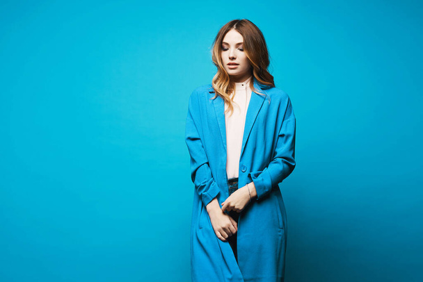 Model girl in blue coat and blouse isolated at blue background with copy space. Female fashion. Beauty concept. European hipster girl. - Photo, Image