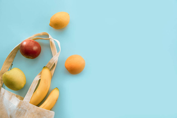 Frutas en una bolsa de tela, plátano, manzanas, limón y naranja. Vista superior, plano, espacio de copia. Concepto de cero residuos
. - Foto, imagen
