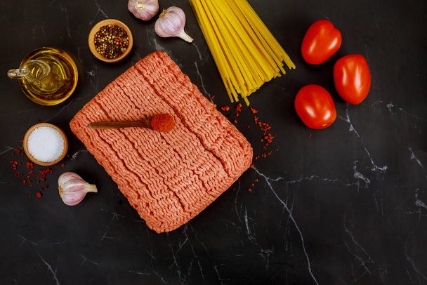 Spaghetti, tomato, olive oil, garlic, ground beef on black background top view - 写真・画像