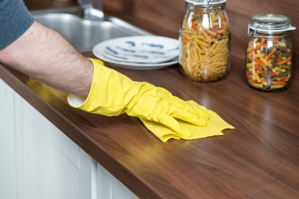 dans la cuisine, ils essuient la table avec des gants jaunes. essuyez la table avec un chiffon
. - Photo, image