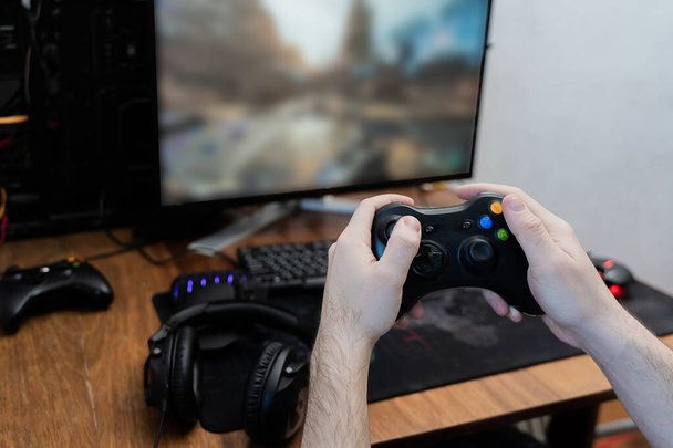een man houdt een spel pad rond een gaming toetsenbord in zijn handen, een spel pad muis. bovenaanzicht - Foto, afbeelding