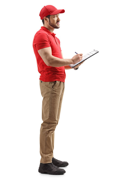 Full length profile shot of a delivery man holding a paper document isolated on white background - Фото, зображення