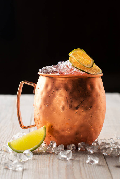 Moscow Mule cocktail in a Copper Mug garnished with dried Lime and ice on black background - Photo, image