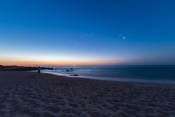 Dawn at the sea. A silhouette of a woman in the distance. Sea coast, stones. Black Sea. - Photo, Image