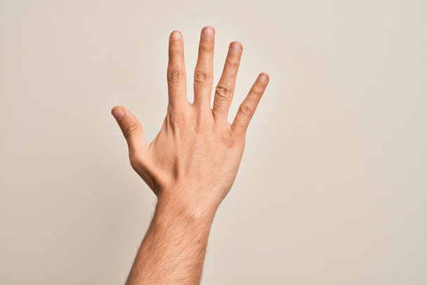 Mão de jovem caucasiano mostrando dedos sobre fundo branco isolado contando número 5 mostrando cinco dedos - Foto, Imagem