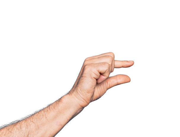 Mano de hombre caucásico de mediana edad sobre fondo blanco aislado recogiendo y tomando cosa invisible, sosteniendo el objeto con los dedos mostrando el espacio - Foto, Imagen
