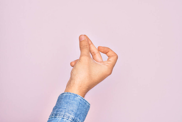 Hand of caucasian young man showing fingers over isolated pink background snapping fingers for success, easy and click symbol gesture with hand - Photo, Image