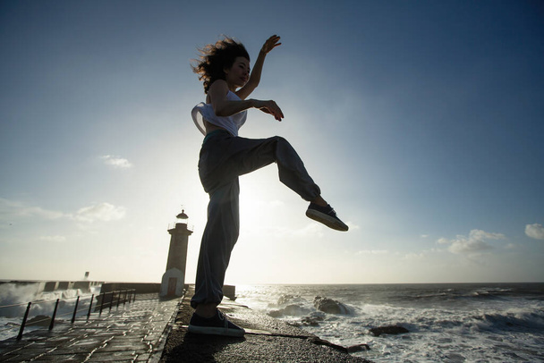 Mladá smíšená žena tančící na atlantické promenádě.  - Fotografie, Obrázek