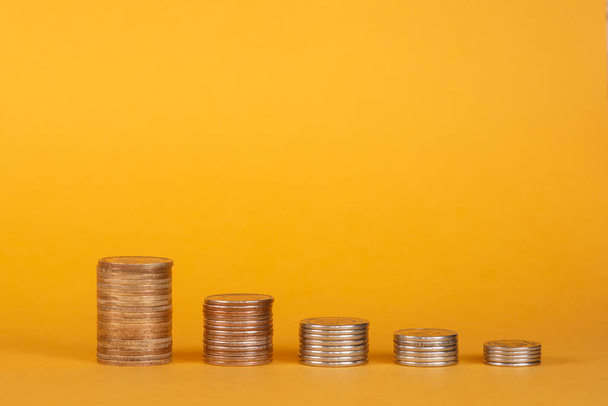 Stack of coins on a orange or yellow background - Foto, Imagen