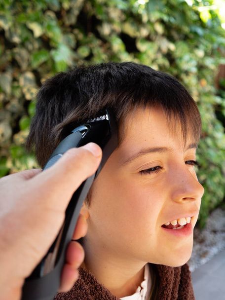 VATER schneidet seinem Sohn zu Hause das Haar, WÄHREN KONFINEMENT - Foto, Bild