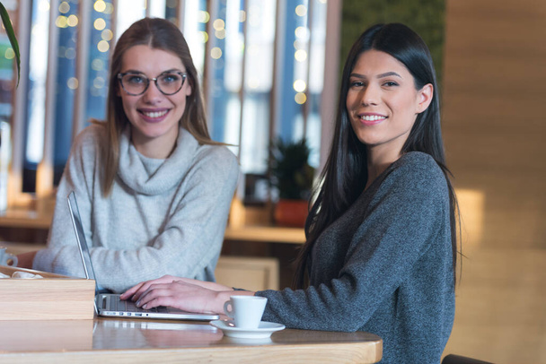 Dvě mladé obchodní ženy spolu mluví o nových projektech v kavárně v caffe brzda. Úsměv do kamery - Fotografie, Obrázek