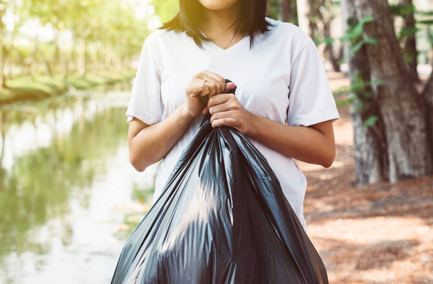 Women volunteer holding black color garbage bag at outdoor,Dispose waste management and plastic recycle concept - Foto, imagen
