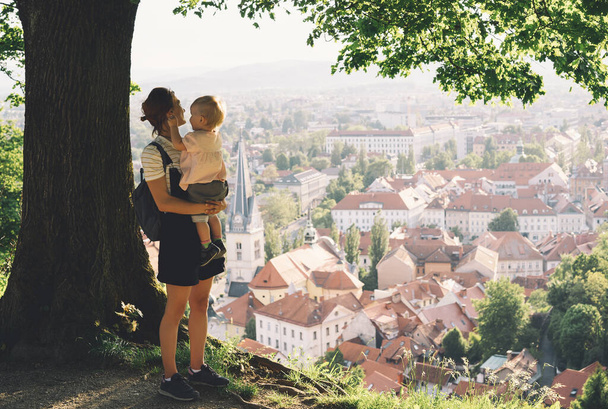 Family on background of Ljubljana, Slovenia, Europe. Woman with her child girl look at panorama of european city from the hill. Mother and kid outdoors at spring or summer time. - Fotoğraf, Görsel
