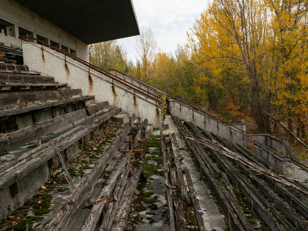 Abandoned decaying tribune of sport stadium Avangard, taken by nature in Pripyat ghost town in Chernobyl Exclusion Zone. Ukraine - 写真・画像