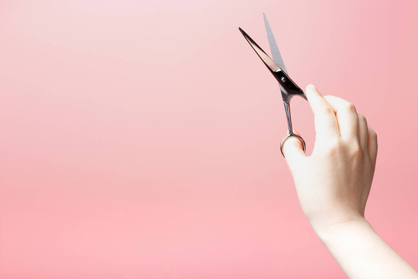 A woman's hand holds hairdressing scissors, on pink background, copy of the space - Fotó, kép