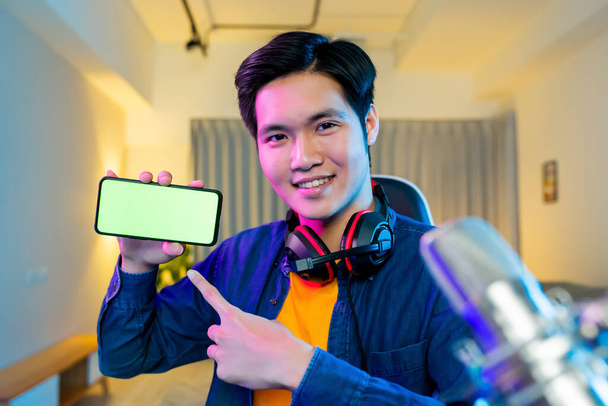 asian man internet celebrity have a live stream and show app on the smartphone with green screen at home - Zdjęcie, obraz