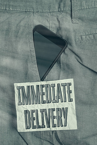 Text sign showing Immediate Delivery. Conceptual photo Send it Now Custom Procedure to dispose Promptly Smartphone device inside formal work trousers front pocket near note paper. - Photo, Image