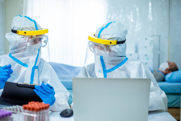 doctors discuss patient situation on computer with the isolation gown or protective suits and surgical face masks - Photo, image