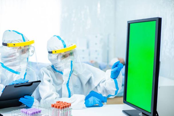 doctors discuss something on green computer screen with the isolation gown or protective suits and surgical face masks - Φωτογραφία, εικόνα