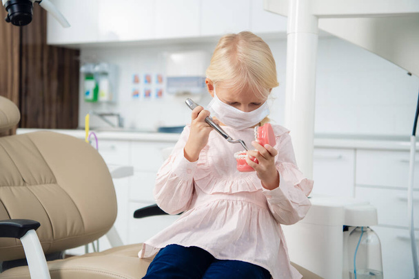 Маленька блондинка грає у стоматолога в клініці
 - Фото, зображення