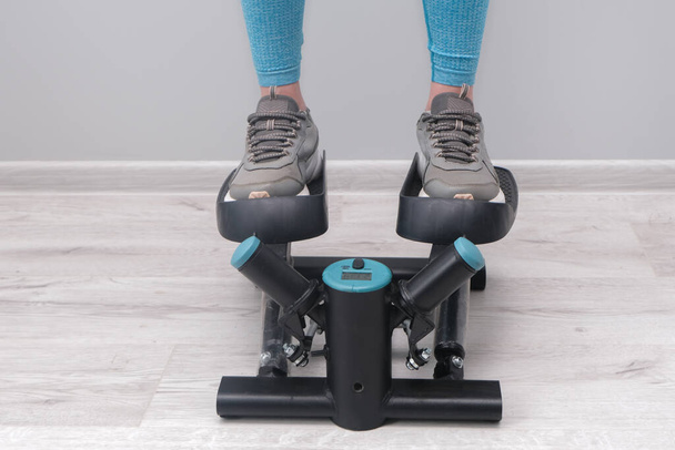 Ноги женщины, упражняющейся на поворотнике ступеньки. Цифровой дисплей, поддерживающий форму дома
.  - Фото, изображение