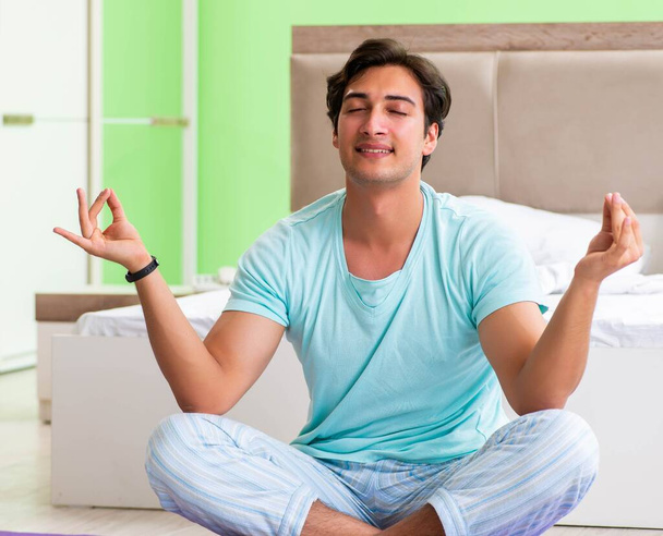 Young man in pajamas doing morning exercises - Photo, Image